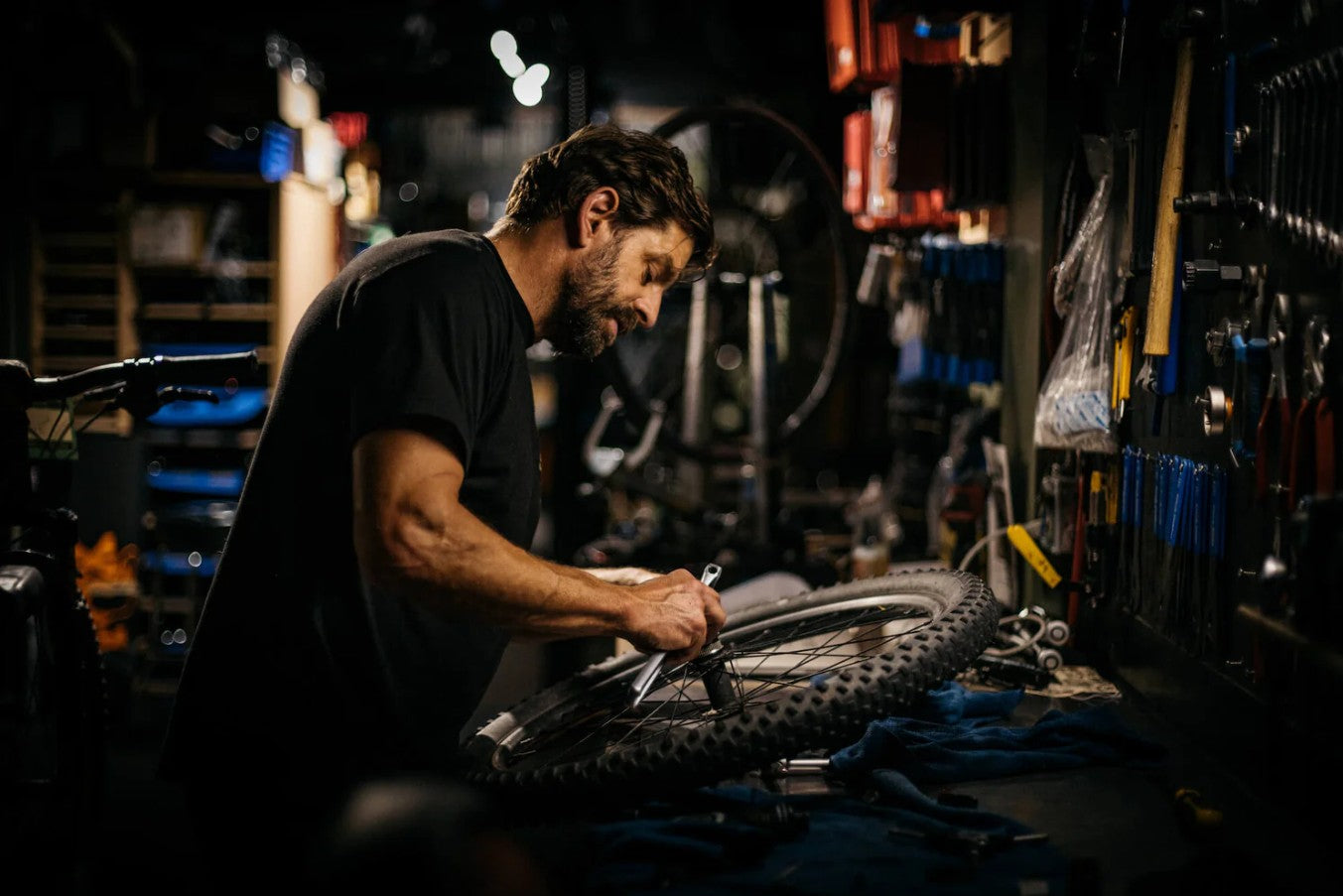 Wade Simmons working on a bicycle in a workshop with tools and equipment around